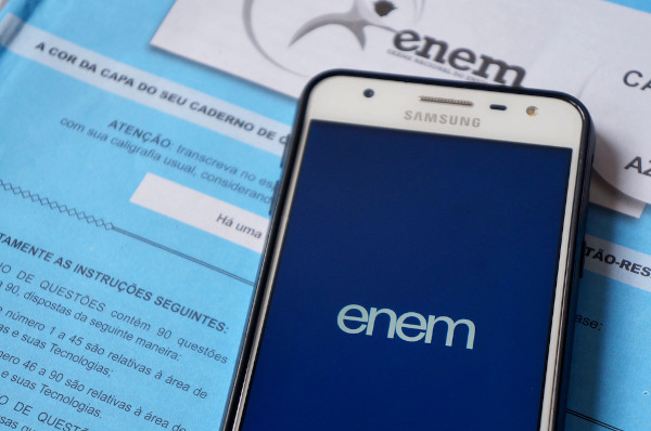 Celular aberto no aplicativo do Enem sobre um caderno de provas do exame.